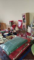 Photo of assorted Christmas decorations, including glassware with Santa designs and linens wrapped in plastic.