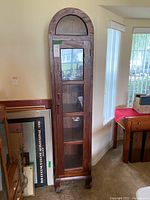 Full view of the tall wooden display cabinet showing its arched top and glass panels on three sides.
