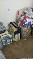 Photo of various folded and bagged quilts and bedspreads on carpet near wall