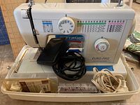 Euro-Pro sewing machine with foot pedal, power cord, and accessories in the case