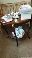 Full view of wood side table with bakeware on top and bottom tray, placed in front of two wooden chairs.