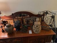 Ceramic jar with lid and various decorative items on wooden sideboard including sculptures and metalwork