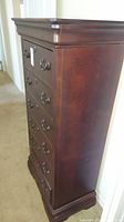 Side view showing dark wood finish and decorative top molding of dresser.