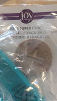 Light blue Joy Super Chic handheld/stick vacuum cleaner visible through plastic packaging alongside product label