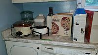 Two Rival Crock Pots, Moulinex juicer, fondue pot, and panini press box on countertop