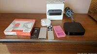 Wide shot showing all items in the lot including Apple TV, two iPods, EarPods, case, and USB cable.