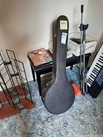 Banjo case standing among other items on carpeted floor