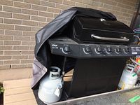 Master Chef Select 5B propane BBQ grill with cover partially removed, showing black body and control knobs.