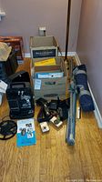 Overview of Bell and Howell 8mm projector with reels, instructions, and cases on the floor.