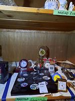 Photo of the lot showing five different clocks on a table; includes clock with family photo frames, glass dome pendulum clock, musical drum set clock, office style clock pen holder, and small clocks.