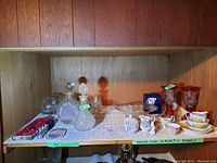 Overview of lot including decanters, red crystal vases, china tea cup and creamers, clear glass bowl, and bar accessories.