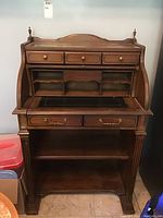 Front view with roll-top open showing cubbyholes, three top drawers, leather writing surface and lower shelf