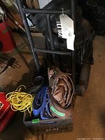 Photo of heavy duty dolly showing metal frame with attached tag indicating 800 lb capacity. Tarps and rope placed in a black plastic crate in front.