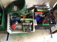 Overall view of the garden supplies including seed bags, spray bottles, and pest control traps in plastic crates.