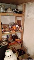 Photo showing shelving with Halloween decorations, platters, napkins, and other items, with plastic ghost figure in foreground