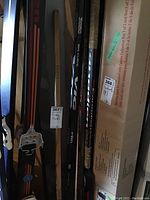 Photo showing grouped hockey sticks leaning against a wall with visible wear and tape on grips.