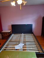 Queen size Ikea Brimnes bed frame assembled showing black headboard with shelves and slatted wooden base with metal supports
