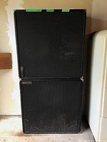 Front view of two stacked Kroth speakers showing textured black cabinets and fabric covers with brand badges.