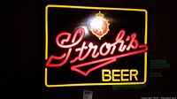Front view of Stroh's Beer lighted sign illuminated showing neon text and emblem.