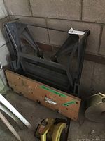 Foldable metal frame work bench with wooden top, showing wear and rust, vise attached on side