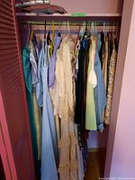 Closet view showing multiple hanging vintage women's clothing including dresses, jackets, skirts in multiple colors and fabrics.