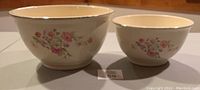 Both Homer Laughlin mixing bowls shown side by side on a flat surface, showing overall size difference and floral decoration on cream background.