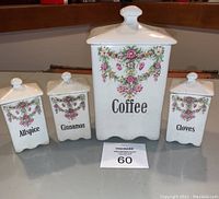 Full view of the antique ceramic coffee and spice set including one large coffee canister and three smaller spice holders with floral garland decoration and black text labels