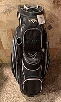 Front view of the black Callaway golf bag showing front zippered pockets, logo patches, and padded club dividers.