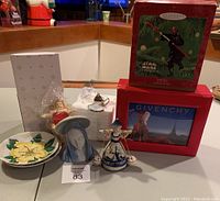 Photo showing the Hallmark Star Wars Darth Vader ornament box, Givenchy vinyl Christmas box, German tagged chubby angel ornament, vintage Germany Art Deco Madonna figurine, two decorative plates, and Hawaiian flower decorations.