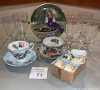 Full lot showing all items including wine glasses, cups and saucers, art plate, and napkin rings.