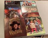Photo showing front covers of 8 vinyl records including Elton John's Greatest Hits Volume 2, Waylon Jennings Greatest Hits, The Rattles, Eagles, and REO Speedwagon.
