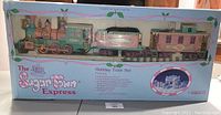 Full view of Enesco Precious Moments Sugar Town Express holiday train set inside original box, showing packaging design and arrangement of train cars.