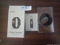 Befitrack fitness tracker set with box, user manual, and black tracker band wrapped in plastic.