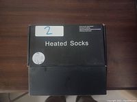 Closed black box with 'Heated Socks' text and icon depicting socks. Also includes note of nano touch operation and rechargeable battery (battery not included).