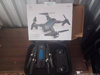 Photo showing the Deerc D10 drone folded with its remote controller and the original box in the background.