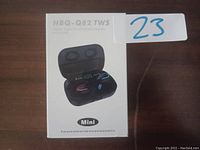 Front view of HBQ-Q82 TWS earbuds packaging showing the product image and model number on a brown wood surface.