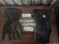 Pair of black Intelligent Heating unpadded gloves, medium size, laid out flat on a dark surface with label reading 'Intelligent Heating Gloves M'