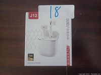 Photo of the unopened product box of J12 wireless earbuds in white color, showing front view with earbuds and charging case image and branding.