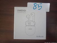Photo showing the UMIDIGI True Wireless Airbuds box with an illustration of the earbuds and charging case on the front. The box is white with the UMIDIGI logo and product name.