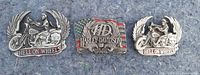 Front view of three Harley-Davidson belt buckles, two with 'Hell on Wheels' biker design and one with logo and flag.