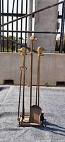 Front view showing brass fireplace tools in holder with duck head handles.