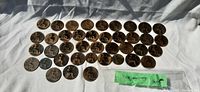 Wide view of all large British pennies arranged on white cloth, showing the reverse side with seated Britannia design.