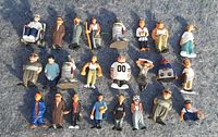 Photo showing 20 collectible Homies figurines arranged on a grey surface, featuring a variety of characters with urban streetwear styles, including one seated figure in a wheelchair.
