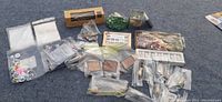 Full view of crafting supplies including hot glue gun, beads, googly eyes, feather pen and stones spread on carpeted surface.