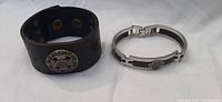 Photo showing both Harley-Davidson bracelets, one black leather cuff and one silver-tone linked bracelet