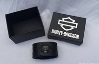 Black Harley-Davidson box, lid removed, showing open interior next to cuff bracelet.