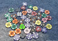 Photo showing a variety of multicolored collectible poker chips from Harley-Davidson, spread out on a gray surface.