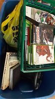 Blue bin with green basket holding cases, cords and books