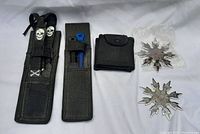 Photo showing two black nylon pouches, a small pouch, and two metal throwing stars, one with spikes and rust.
