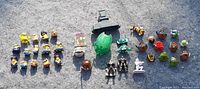 Multiple small toys including about 20 Minions figures, some Star Wars figures, and small Angry Birds toys laid out on a grey surface.